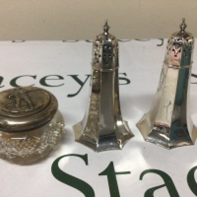 A pair of quality silver condiments with octagonal tapering cylinders Sheffield hallmarks weight approximately 170g and a silver topped jar decorated with a North American Indian. (3)
