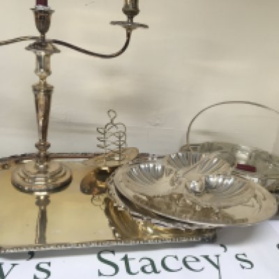 A large silver plated tray other silver plated serving dishes a candelabra orderve dish and other plate.