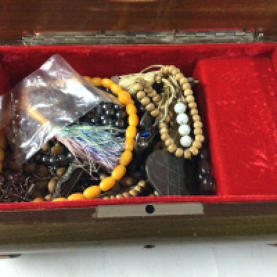 A wooden jewellery box containing cross pendants, rosaries and prayer beads.