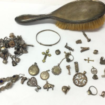 A collection of silver charms, a silver brush and silver oddments . Postage cat B