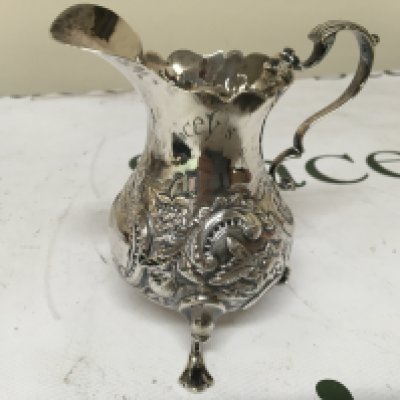 A Silver cream jug repousse chased with scroll handle and feet marks to the base. Weight 120g
