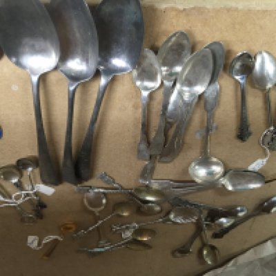 A collection of various spoons including silver , enamel and plated .