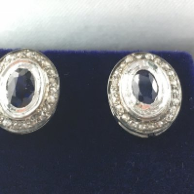 A pair of silver studs set with oval sapphires and diamond halos. Sapphires approximately 0.45ct and diamonds 0.25ct. Postage B