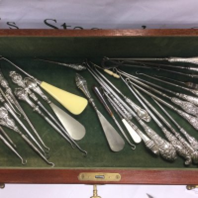 A collection of silver handled button hooks in a display case. Shipping category D.