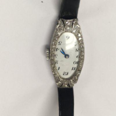 A Art Deco platinum watch the shape dial with Arabic numerals surrounded by diamonds.