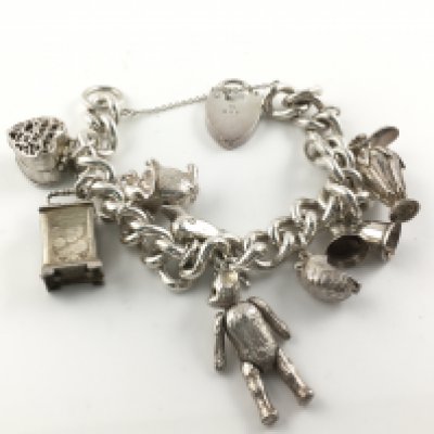 A silver hallmarked charm bracelet with multiple charms. 99g Postage B