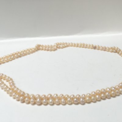 A 64 inch long cream pearl necklace , postage category A