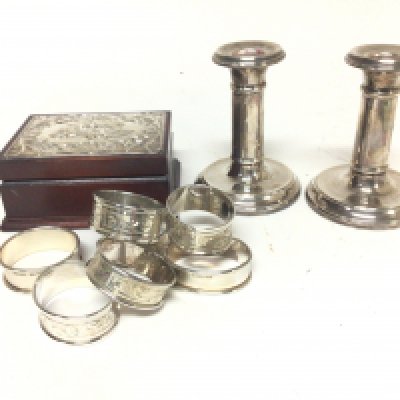 A collection of silver napkin rings a silver mounted trinket box and a pair of candle sticks with loaded bases.