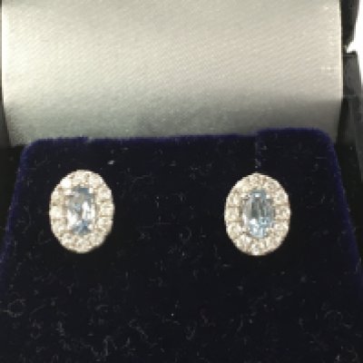 A pair of white gold oval aquamarine and diamond cluster studs. Aquamarine 0.52ct and diamonds 0.31ct. Postage B