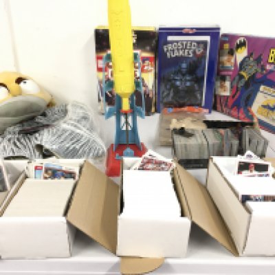 A varied lot comprising gaming and baseball cards..a pair of rubber masks&hellip;Batman items &hellip;atlas rocket launcher and two unopened boxes of cereals with free gifts the use by date has expired . No reserve