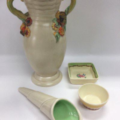 Three Clarice Cliff items comprising a two handled vase, approx height 30cm, a conical wall vase and a square dish plus a small Susie Cooper dish (4). Shipping category D.