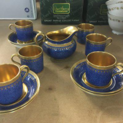 A cauldron blue ground coffee set with applied gilt work . Comprising cups saucers and milk jug .