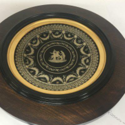 A 19th century Wedgwood plaque black basalt Jasperware of Robert Adam design influence with classical figures rans heads and garlands marks to the reverse in a later frame total diameter 36cm scratch marks to the reverse which are not cracks.
