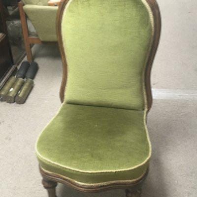 A Victorian walnut chair wit carved top rail and green upholstery on turned legs.