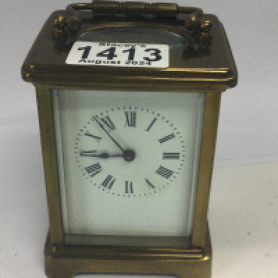 A brass carriage clock the dial with Roman numerals.