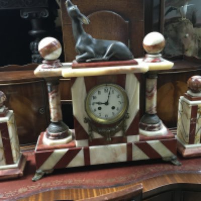 A Art Deco red and green marble mantel clock garniture cthe circular dial with Arabic numerals the top surmounted with a deer .40 x 48 cm .