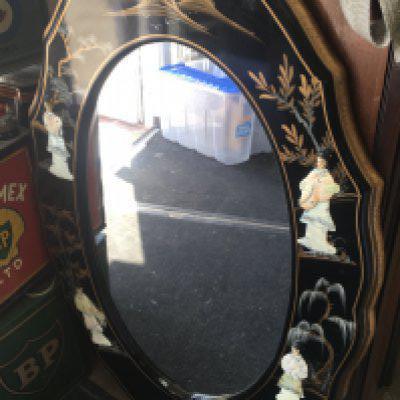 A oval Chinese style wall mirror decorated with raised figures trees and foliage. 50 cm x 90 cm