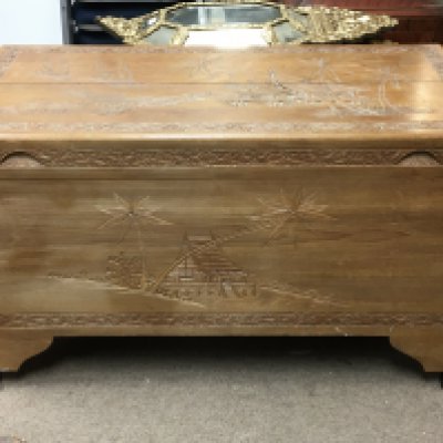 A Camphore wood trunk with carved oriental style design of temples and a ox cart. Dimensions 50x100x58cm