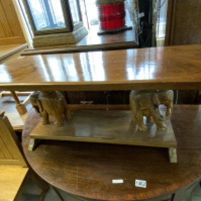 A carved hardwood table the pillars in the form of elephants. 96cm x 38cm x 34cm.