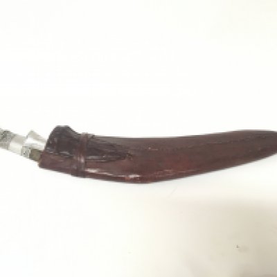 A large old Kukri Knife in a patterned leather scabbard with a silvered handle and small side knifes.length 60cm