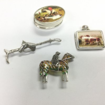 A silver brooch in the form of a horse and rider and three small silver items . Shipping category A.