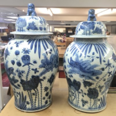 A pair of large Chinese vases with foo dog / lions on the lid. Repair visible to the rim of one. Approximately 70cm tall and 35cm wide.