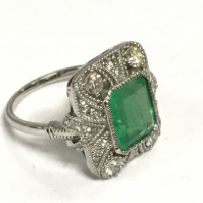A platinum Edwardian style dress ring set with emeralds and diamonds with millegrain and filigree scroll detailing. Step cut emerald approx 2.52ct, RBC and eight cut diamonds approx 0.82ct. Approx 7g and approx size L. Shipping category A.