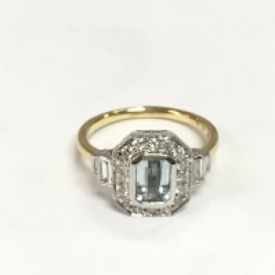 An 18ct yellow and white gold Art Deco style dress ring set with a step cut aquamarine with baguette and RBC diamonds. Aquamarine approx 0.82ct, diamonds approx 0.60ct. Approx 4.5g and approx size O. Shipping category A.