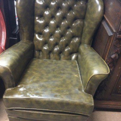 A green leather button back open armchair.