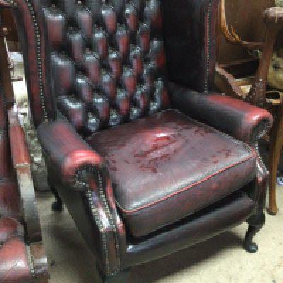 A red leather wing armchair with button back on cabriole cabriole legs .