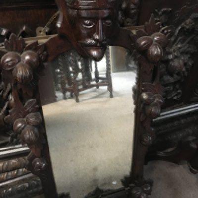 A small mirror carved with a figure head and a Victorian carved wine table .