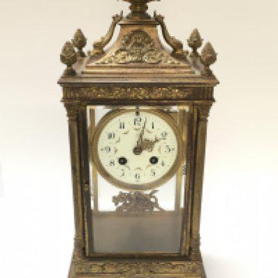 A French early 20th century gilt metal ornate clock with stylised dolphins, urn top, a ceramic dial with hand painted flower decoration, pendulum, striking and gong. This lot cannot be posted