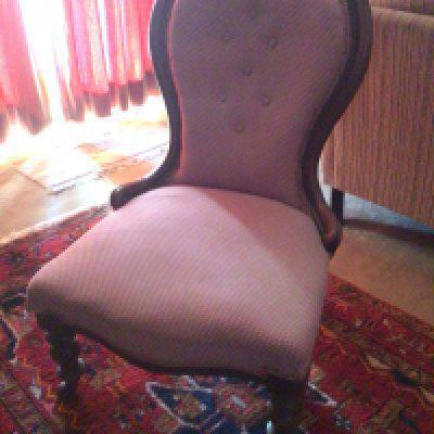 A Victorian chair with shaped back red patterned fabric upholstery and turned legs.