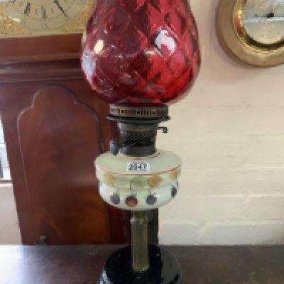 A late Victorian painted oil lamp and cranberry glass shade 58cm.