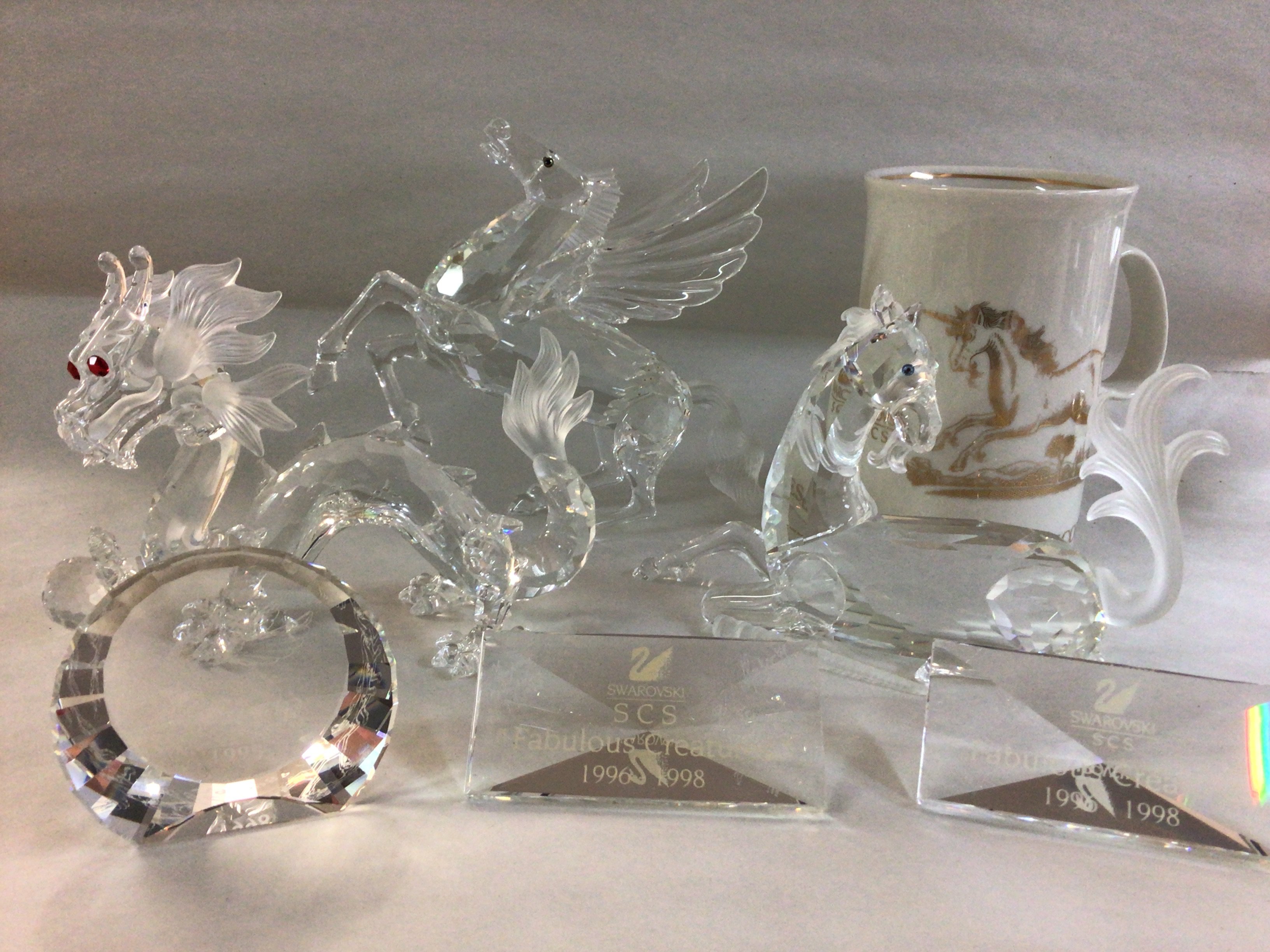 A collection of Swarovski fantasy animals from the Annual Additions 1996-1998 range including Unicorn (A/F) , Dragon and Pegasus- all in fitted boxes with certificates. Plus stands and paperweights