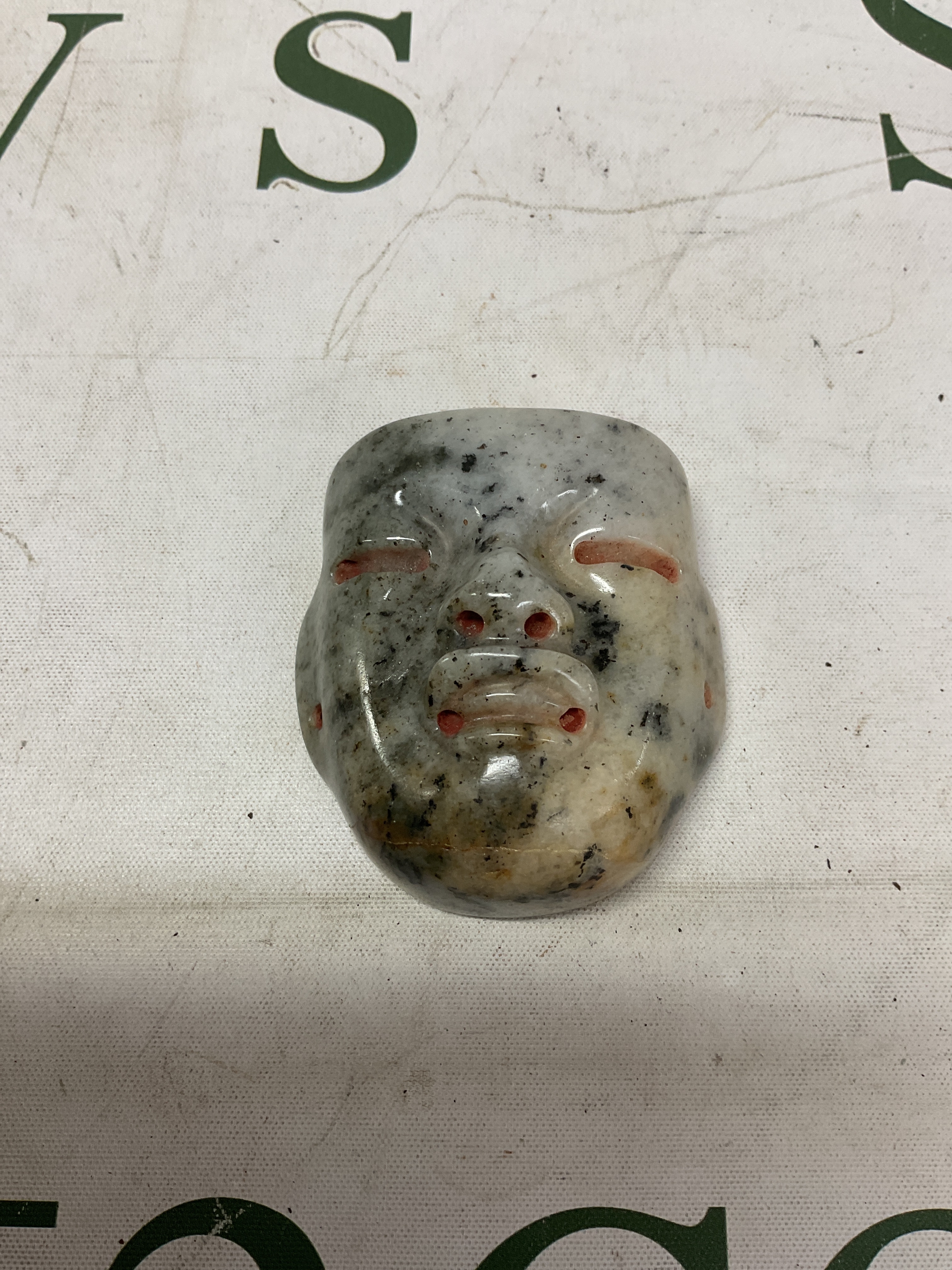 19th C Chinese Jade carved actors mask, in green mottled/mutton fat colours.6cm x 6 cm. With full pierced holes to the sides.