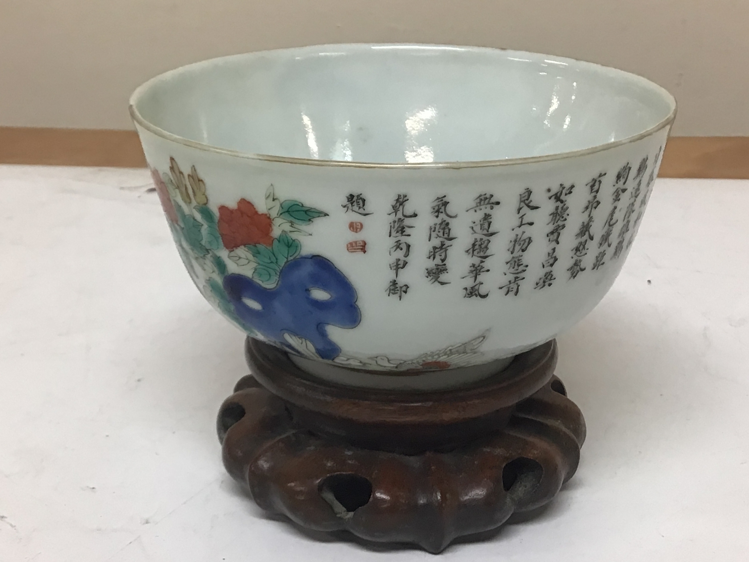 An Early Republic Chinese porcelain bowl decorated with script with polychrome colours caricature marks to the base in red on a hardwood stand no obvious damage Hight 9.5cm diameter 12cm.