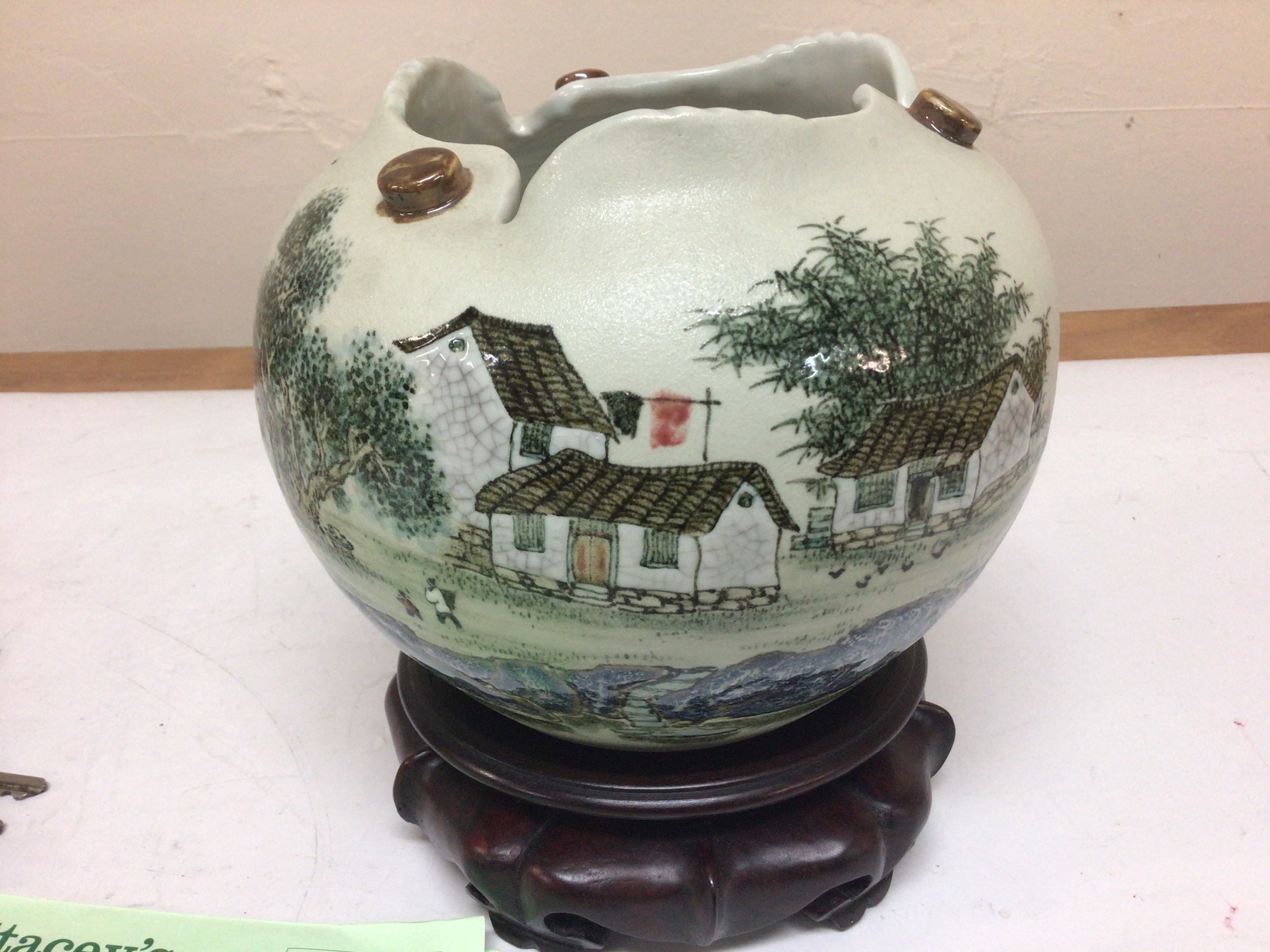 A Chinese late Republic Ceramic art vase decorated in polychrome colours with a rural village scene with figures with a shaped rim and signed base no obvious damage. diameter approximately 20cm with a hardwood stand. 