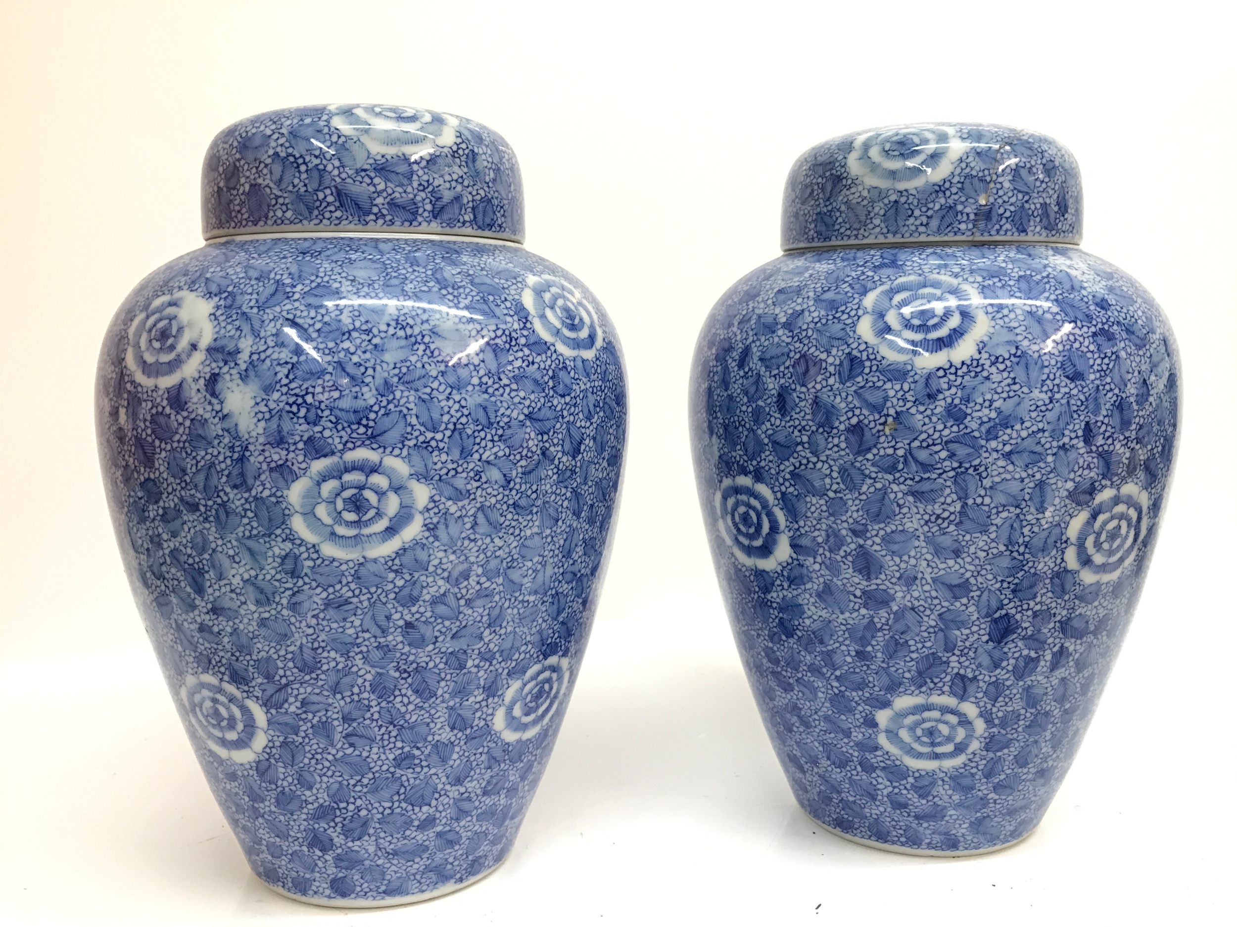 A pair of porcelain Japanese vases with floral lotus motif , lid damaged with hairline cracks. 23cm tall