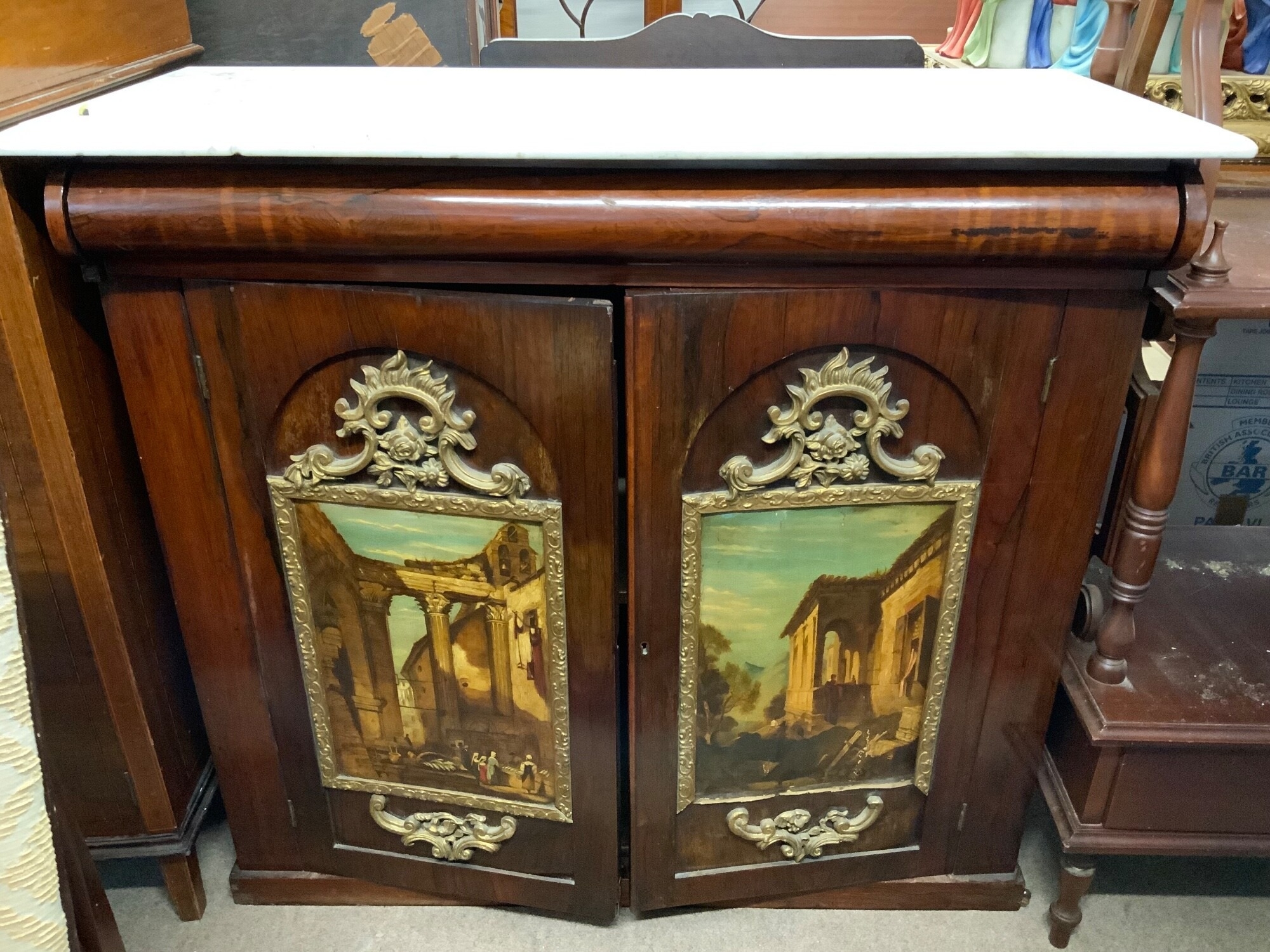 A small marble topped and rosewood topped chiffonier with 2 gilt framed capriccio oil paintings depicting rustic Italian landscapes featuring architectural ruins applied to each door. TO BE SOLD WITHOUT RESERVE