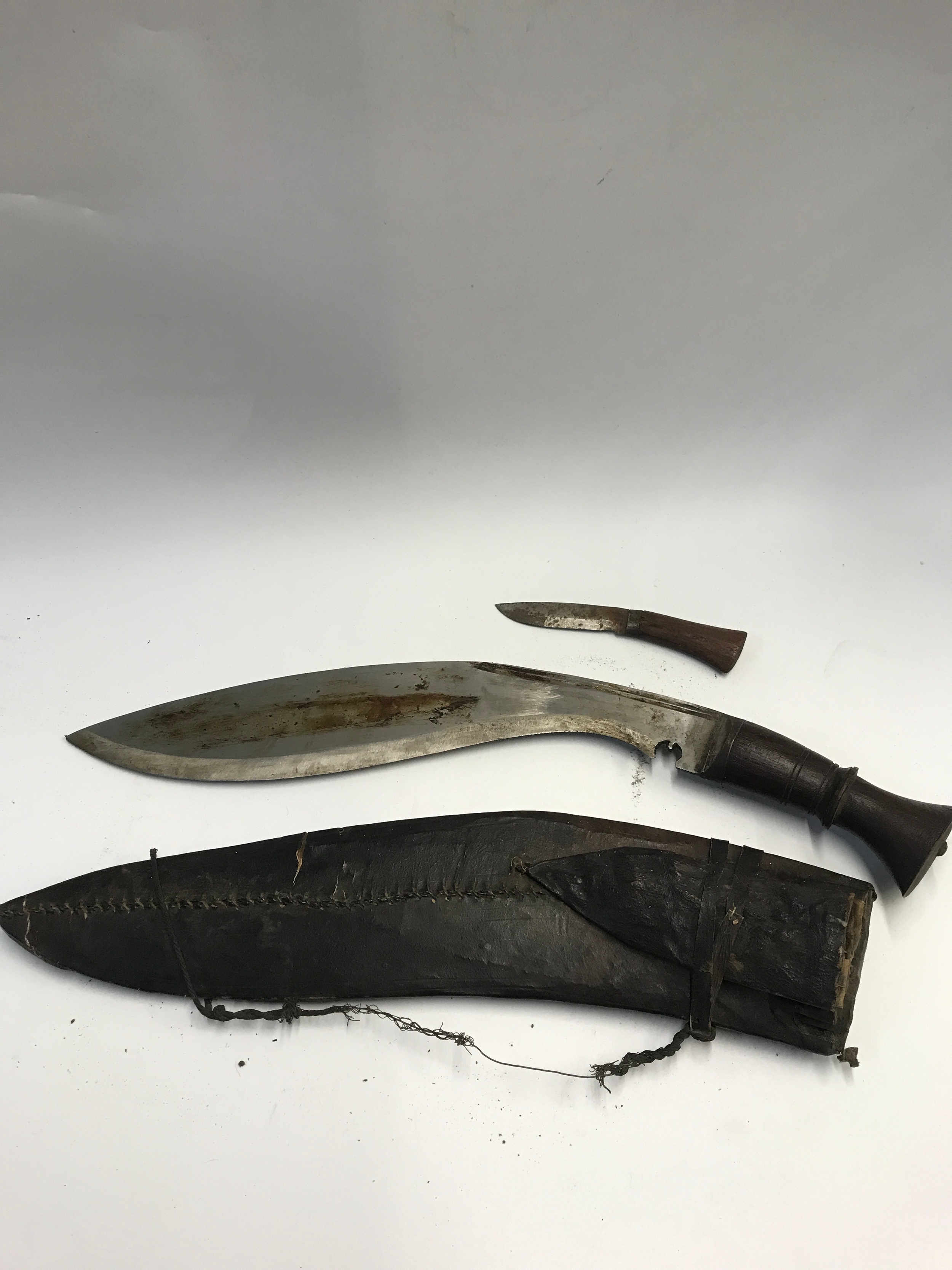 A Nepalese Kukri Knife with a hand stitched leather scabbard and smaller side knife attached. 