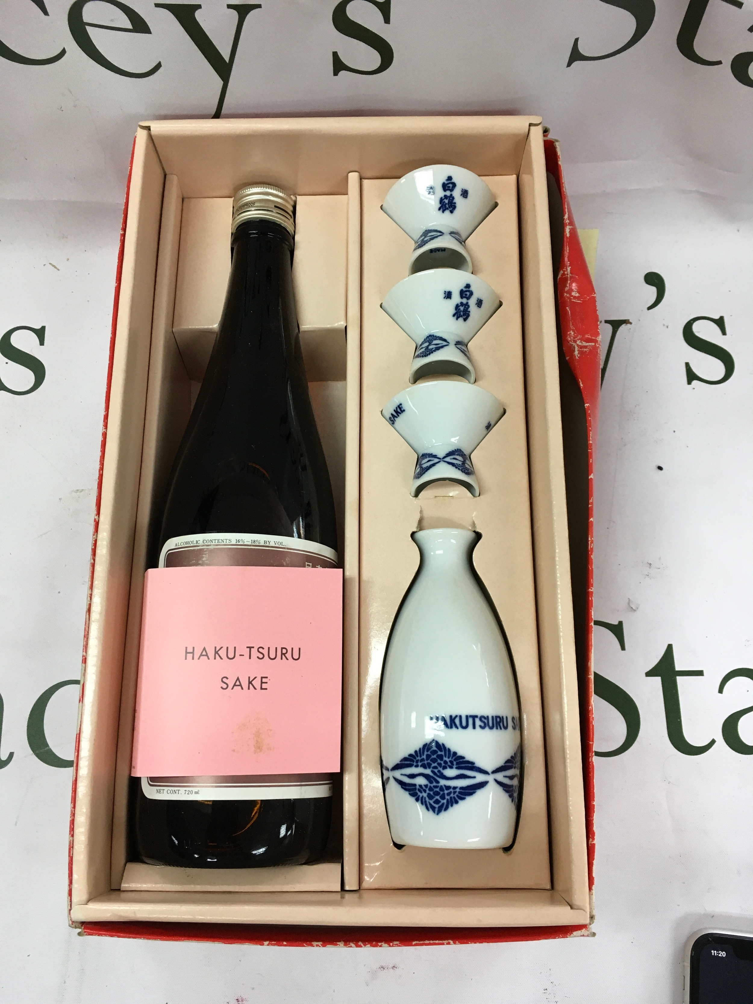 A Hakutsuru brand sake gift set featuring a 720ml bottle and four white porcelain cups with blue traditional designs. 
