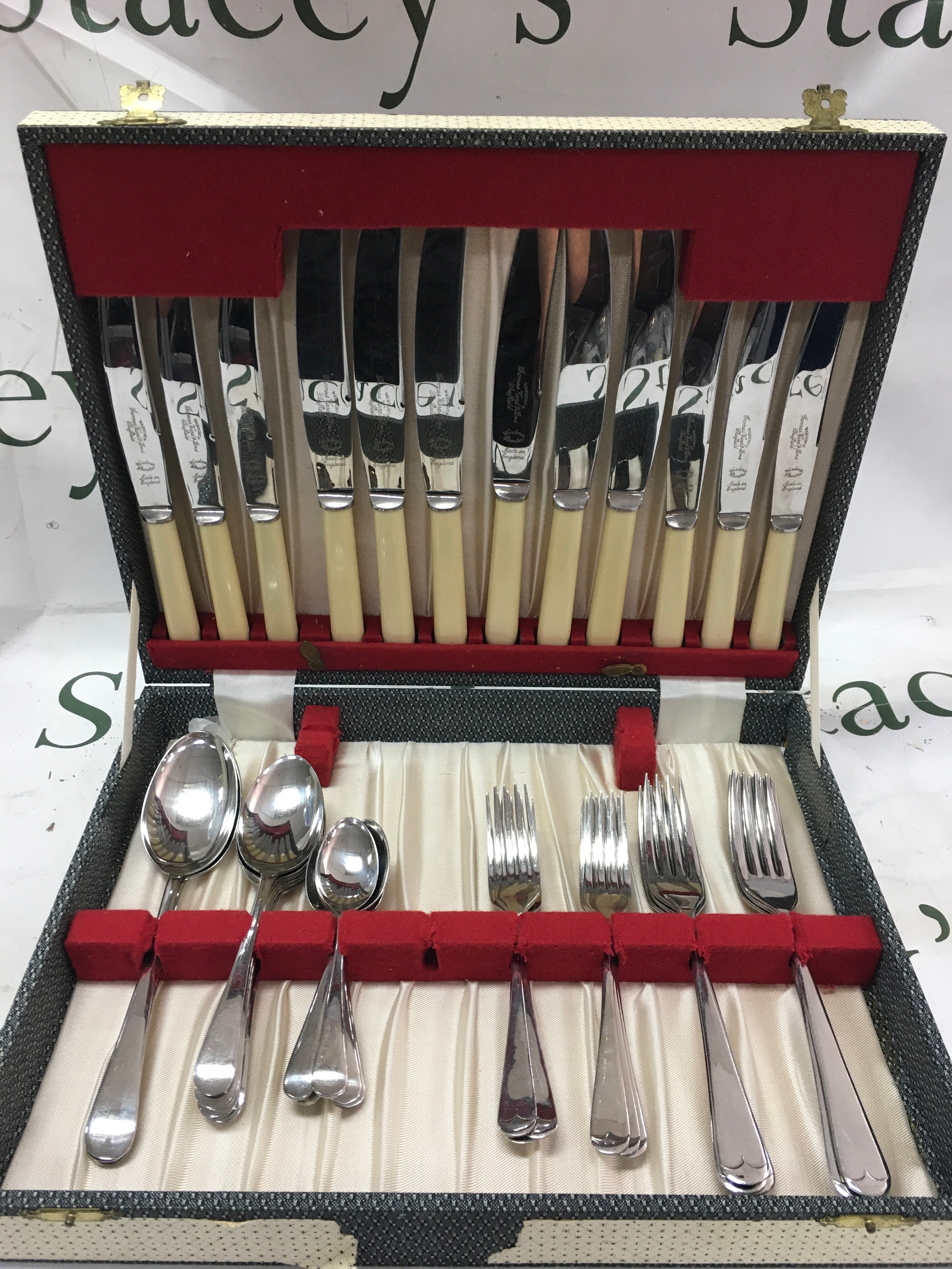 A vintage silver plated cutlery set featuring forks, spoons and knives with faux bone handles. 