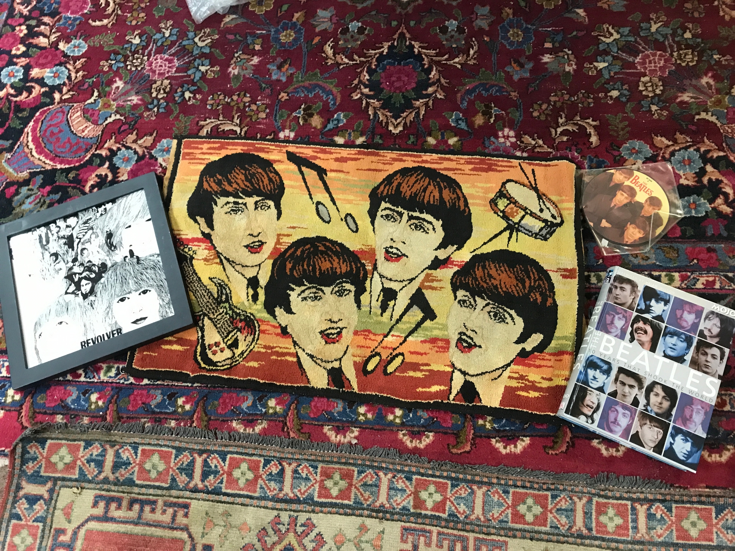 A collection of Beatles memorabilia including a Beatles rug, 10 years that shook the world book, Revolver porcelain display framed, picture disc love me do