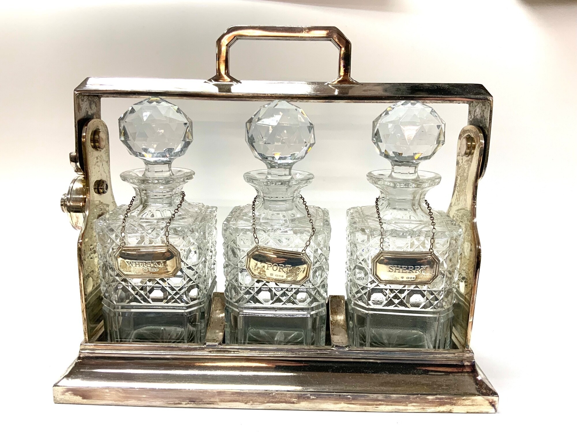 A silver plated 3 bottle tantalus with 3 hallmarked silver wine labels.