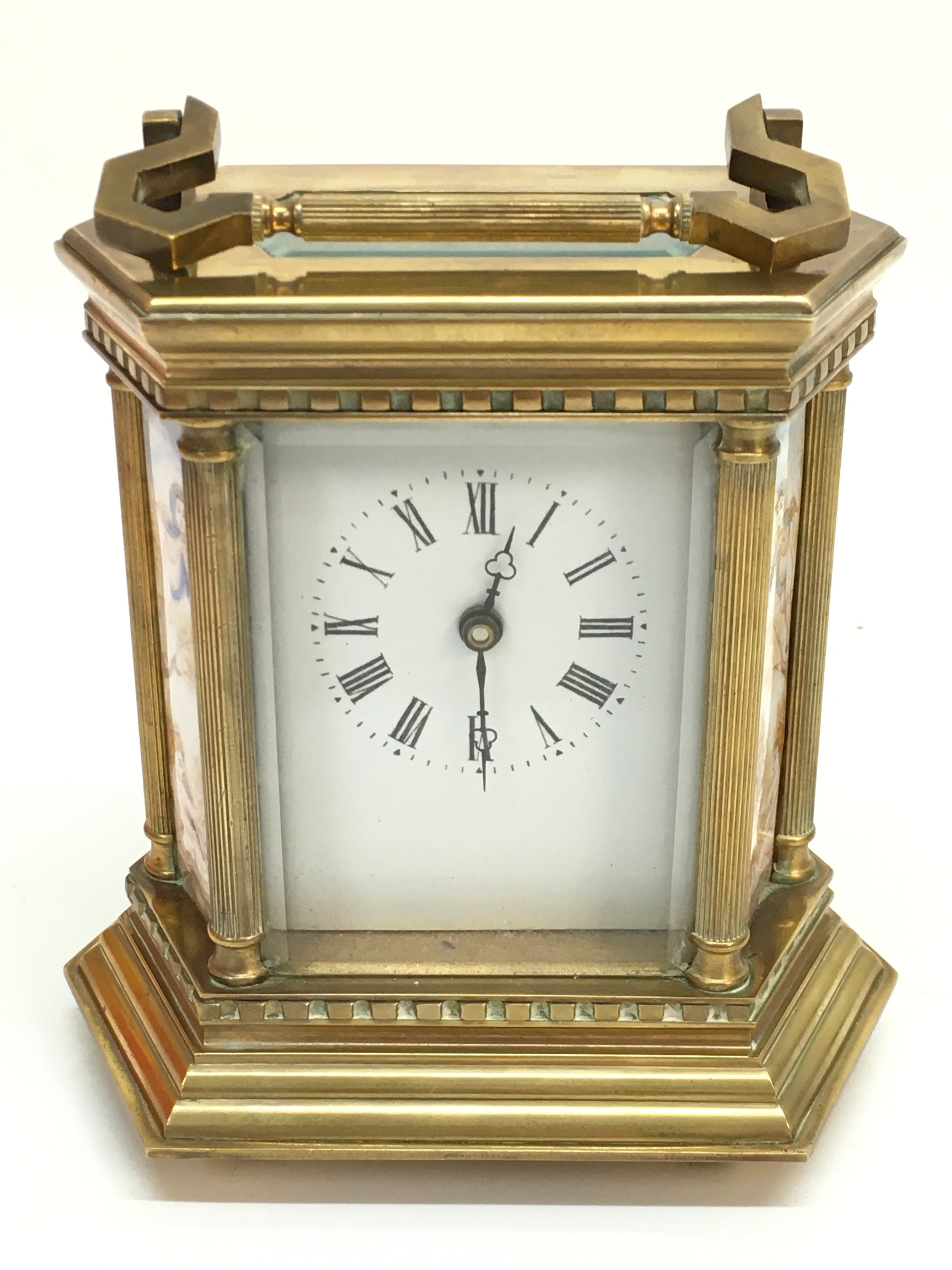 A brass cased carriage clock with ceramic panels. 15cm tall, 13cm wide. With key.
