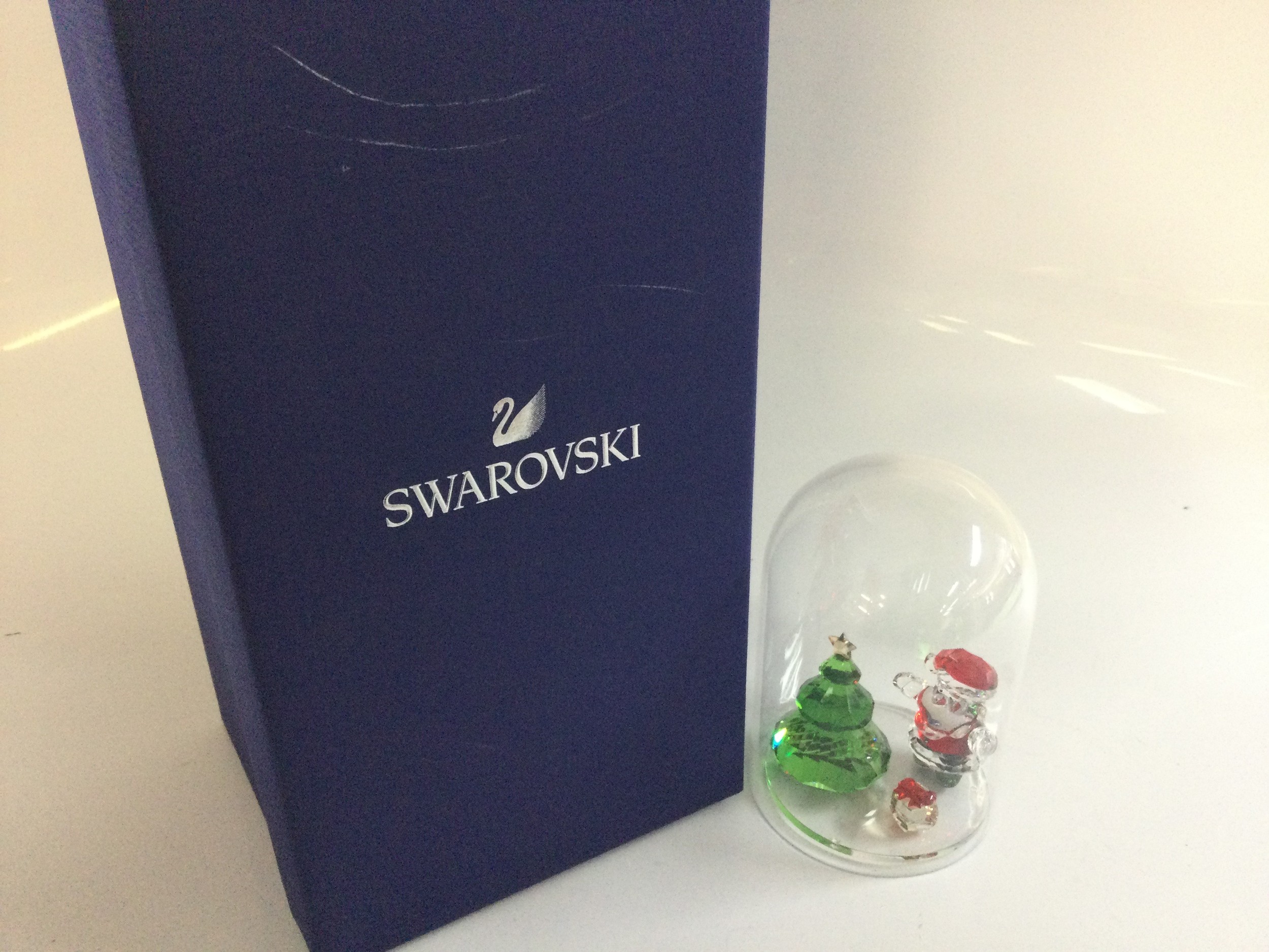 A boxed Swarovski ornament Joyful Bell Jar set (article number 5403170) featuring a Christmas tree and Santa Claus figurines. No obvious damage or restoration