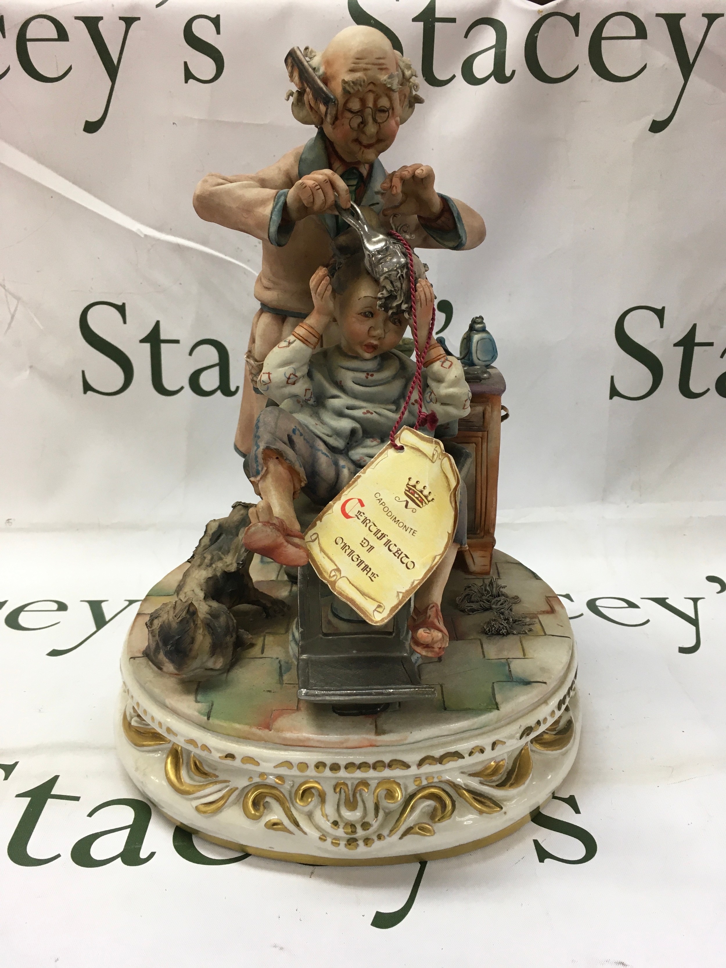 Large Capodimontie figure of young boy at barbers. Signed to back 33cm high.