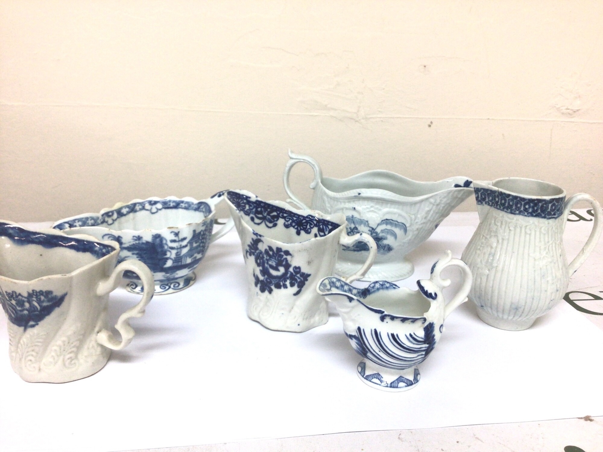 A collection of 18th English porcelain blue and white cream jugs bases without factory marks. With shaped rims and moulded decoration some hairline cracks minor chips. (6)