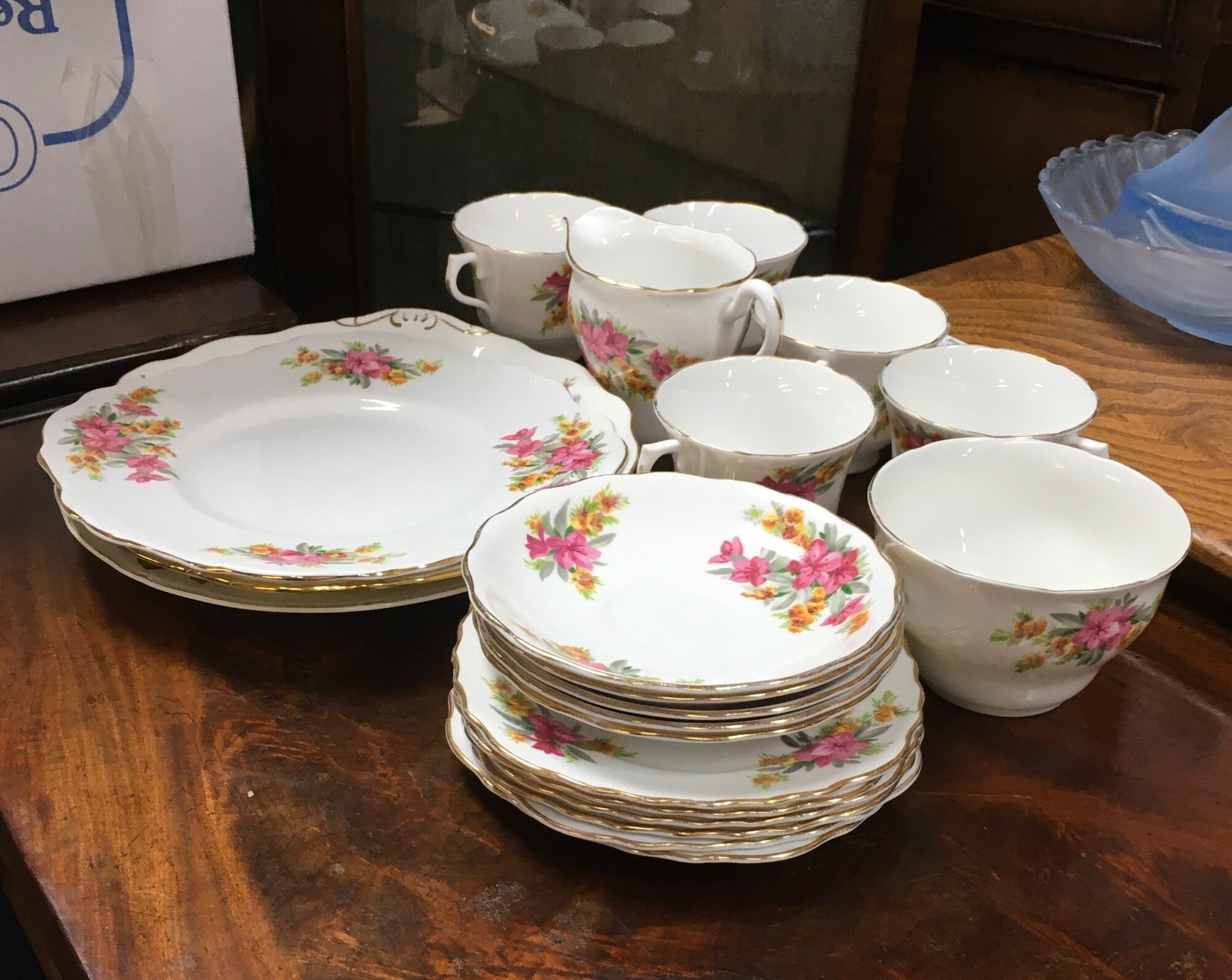 A ceramic tea set decorated with vibrant patterns featuring bright pink blossoms, clusters of small yellow flowers, and rich green foliage. NO RESERVE